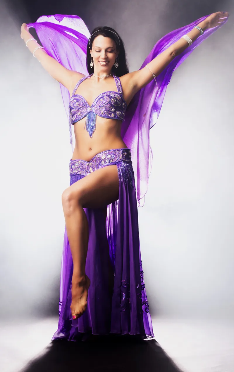 Reischa in a purple beaded costume, sweeping a purple veil
